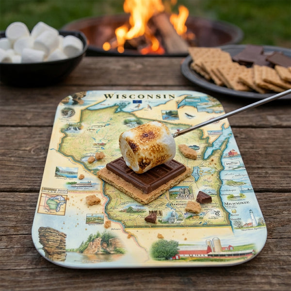 S'mores with a serving tray map of Wisconsin design on a wooden table with a campfire in the background.