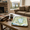 Living room with a wooden coffee table featuring a scenic Lake Tahoe map tray, mug, and sunglasses.