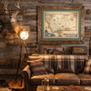 hand-drawn map of the state of Montana hangs above a fireplace on a wood cabin wall.