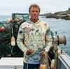 Man wearing a hoodie with a 'Maine' map design on a boat with lobster traps and ocean background