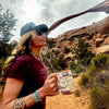 A women holding Arches and Canyonlands National Park ceramic mug. In the background is stone arches