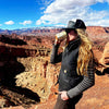 Person drinking from a mug with a scenic view of a canyon in the background
