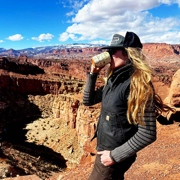 Person drinking from a mug with a scenic view of a canyon in the background