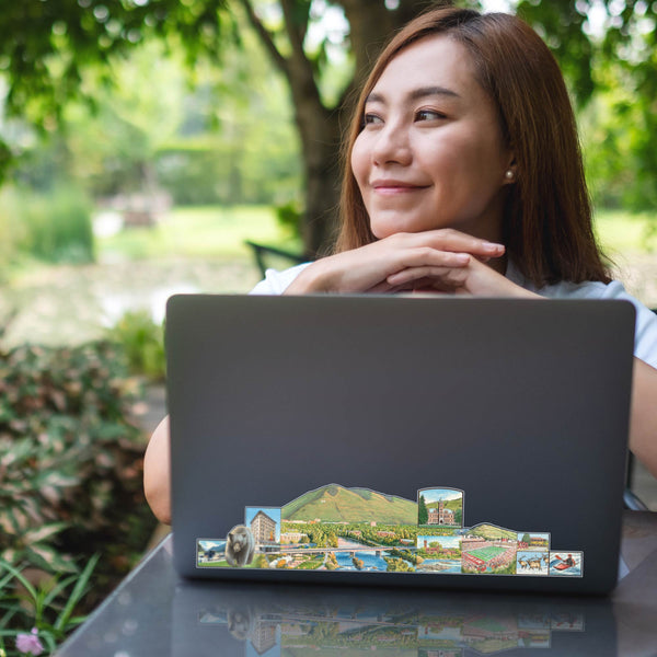 Women sitting with her computer outdoors with a Missoula Map Wrap on the lid of the laptop. 
