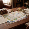 A completed vintage-style map jigsaw puzzle of Montana is displayed on a wooden table in a cozy room setting, surrounded by a mug, magnifying glasses, books, and dried flowers.