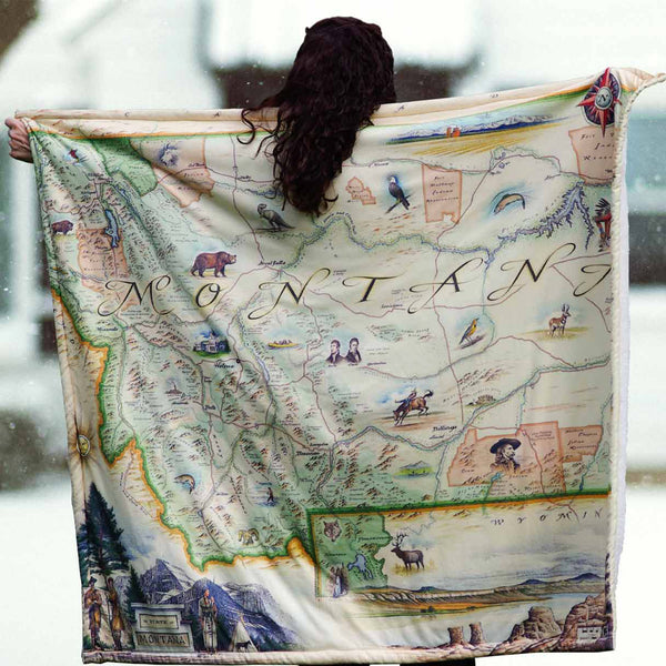 Person holding a blanket map of Montana with illustrations and text.