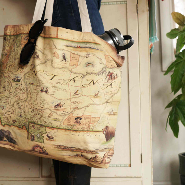 Setting is a cabin kitchen cabinet background: Montana Canvas Tote Bag with a water bottle and sunglass in the bag.