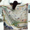 Person holding a blanket map of Montana with illustrations and text.