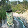 Montana Travel Drinkware sitting on a post over the river. 