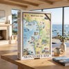 A large jigsaw puzzle box labeled 'Monterey Bay' stands on a wooden table in a bright, modern room with large windows overlooking the ocean. A matching puzzle book lies nearby on the table.