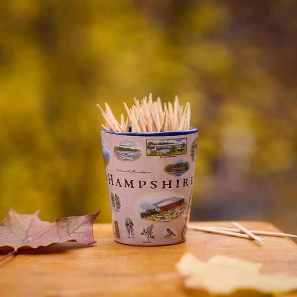 Shot glass of toothpicks with Hampshire design on a wooden surface with autumn leaves.