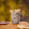 Shot glass with toothpicks labeled 'North Carolina' on a wooden surface with blurred green background