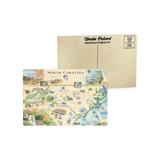 North Carolina state map wooden postcard in earth tone blues and greens featuring hand-drawn illustrations of Blue Ridge Mountains, Outer Banks, and native wildlife like the cardinal and dogwood flower.