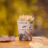 Shot glass of toothpicks with a 'North Cascades' design on a wooden surface with blurred natural background