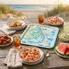 Outdoor dining setup with food and a serving tray 
map of Outer Banks on a wooden table by the beach.