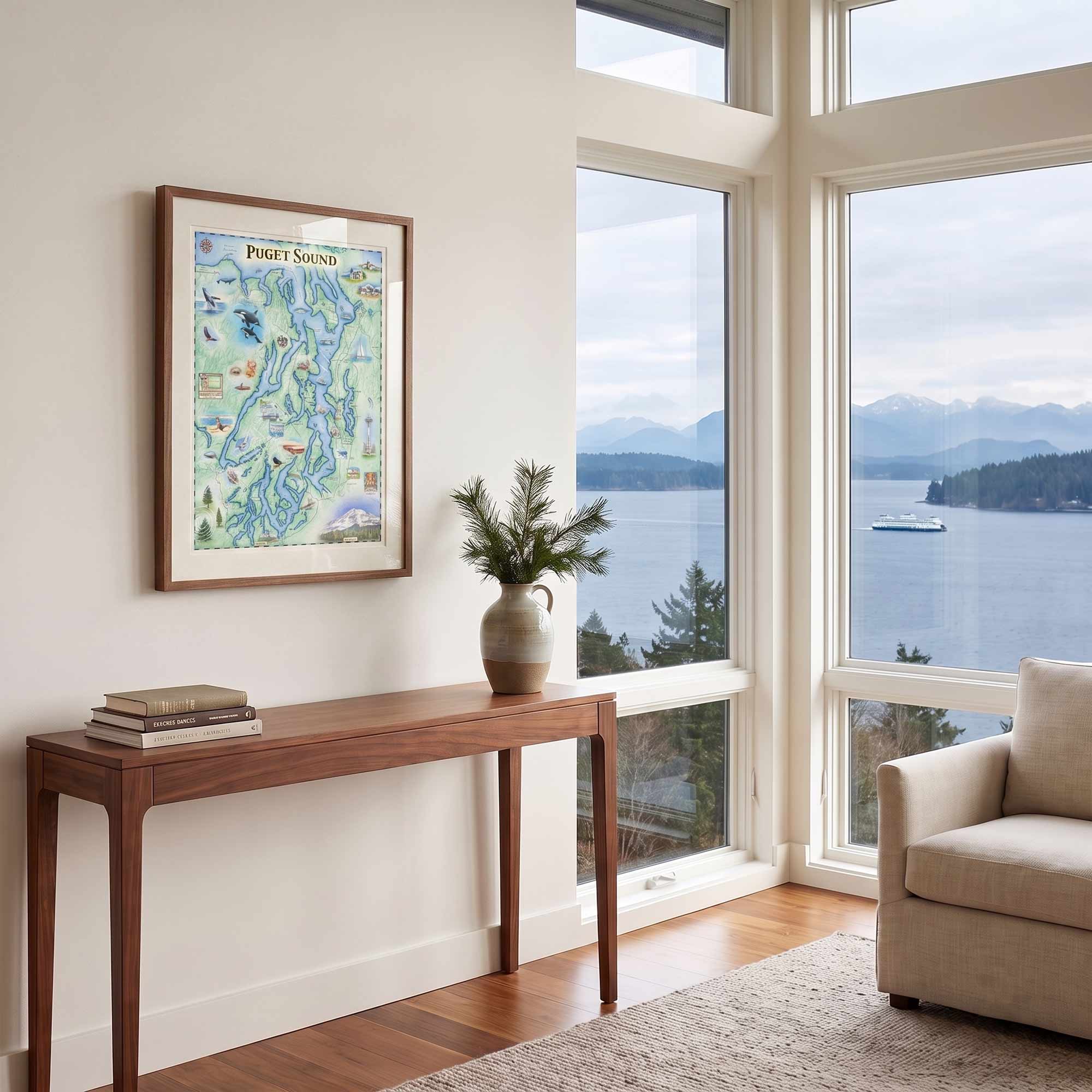 A framed art print of a colorful Port Said map hangs on a white wall in a modern living room with a wooden console table, a vase with greenery, and a large window overlooking a scenic lake and mountains.
