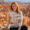 Person wearing a sun shirt hoodie with Red Rock Canyon design, standing in front of canyon landscape.