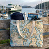 Tote bag with San Juan Islands map design on a wooden bench by a marina.