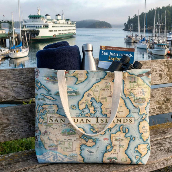 Tote bag with San Juan Islands map design on a wooden bench by a marina.