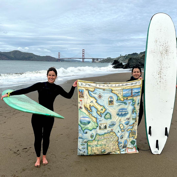 San Francisco Bay fleece blanket being hed up by two surfers. In the background is the Bay and Golden Gate Bridge.  