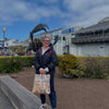 Person standing outdoors with a scenic background featuring a building and statues.