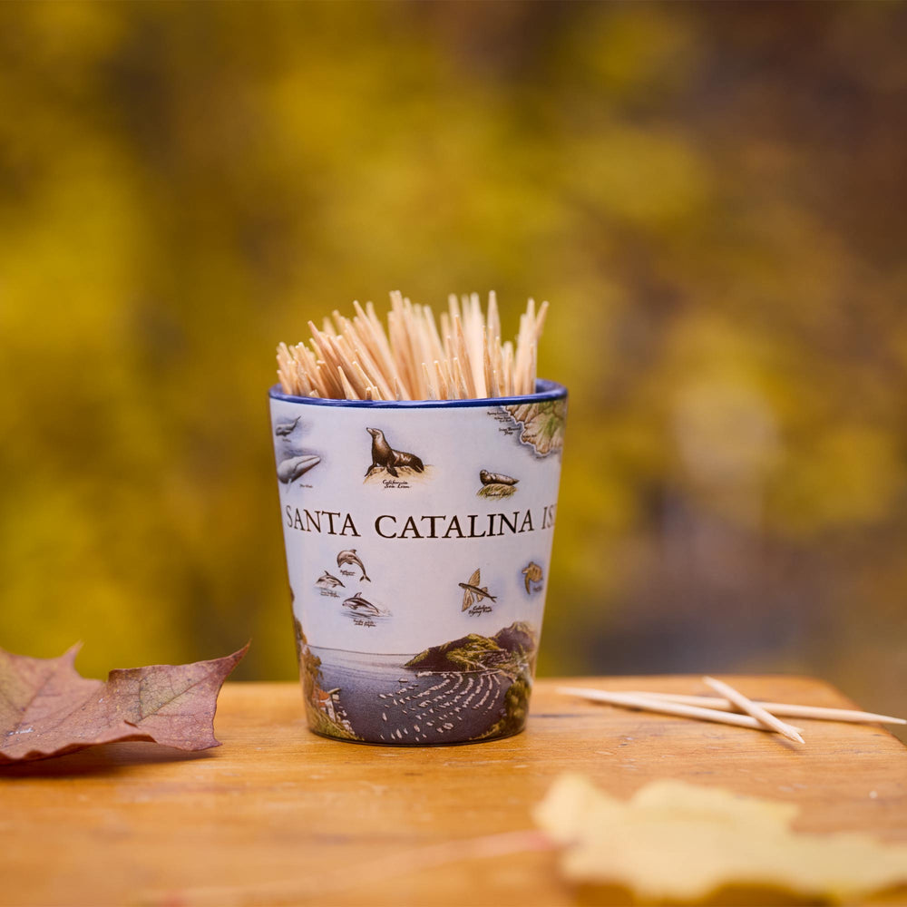 Shot glass with toothpicks on a wooden surface with a blurred natural background
