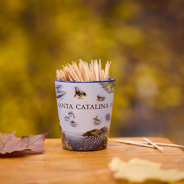 Shot glass with toothpicks on a wooden surface with a blurred natural background