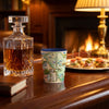 A South Carolina-themed souvenir shot glass with a map design and blue rim, set on a polished wooden table next to a glass decanter in a warm, cozy living room with a fireplace and lamp in the background.