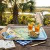 Tray with a South Carolina map, iced tea, and snacks on a wooden table with a scenic background.