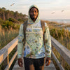 Person wearing a South Carolina-themed hoodie standing on a wooden boardwalk with a scenic background.