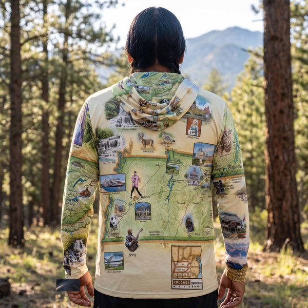 Person wearing a hoodie with a map design of a national park, standing in a forest.