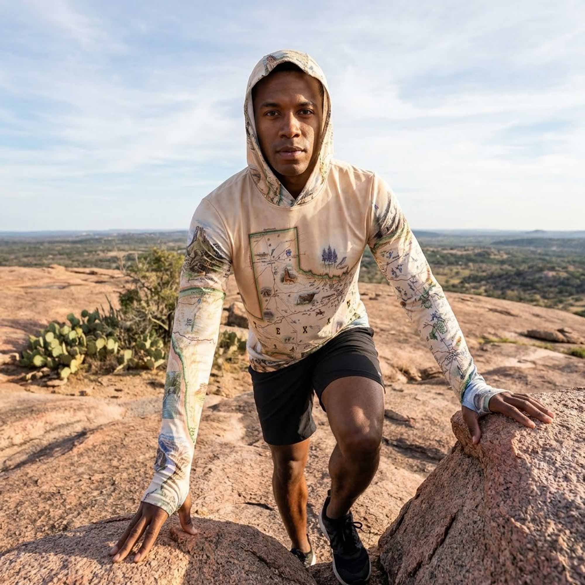 Person in outdoor gear standing on a rocky landscape with cacti and a clear sky.