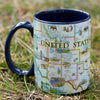 USA Map Ceramic mug with handle sitting on grass in a forest. Blue - 16 oz.