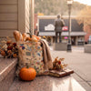 A Utah Canvas tote bag sitting in front of  an orange pumpkin and bread.  