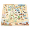 Utah State Map Natural Stone Coasters Set of 4, forming the map of Utah. Each coaster is a work of art, featuring hand-drawn depictions of iconic National Parks like Arches, Canyonlands, Bryce Canyon, Monument Valley, and Zion. The illustrations also showcase popular activities and diverse wildlife, from mountain biking, skiing, and river rafting to dinosaurs, deer, turtles, lizards, and birds.