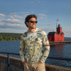 Man wearing a hoodie with Wisconsin map design by a lake with a red lighthouse.