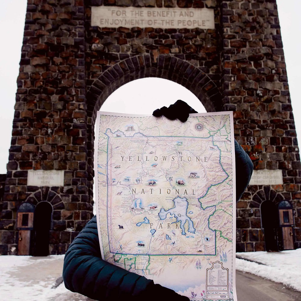 Person holding a Yellowstone national Park Map outside the arches of Yellowstone. 
