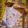 Zion National Park map on a wooden table with a bowl of fruit and snacks in an outdoor setting.