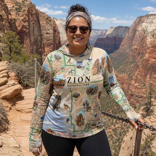 Woman wearing a Zion National Park-themed sweatshirt standing on a trail with canyon views.