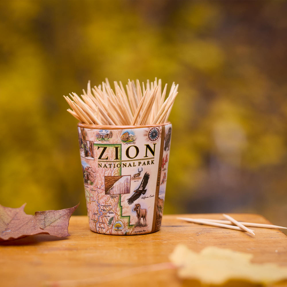 Shot glass of toothpicks with Zion National Park design on a wooden surface with blurred natural background