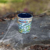 Blue 1000 Island Map Ceramic Shot Glass sitting on a tree stump. 