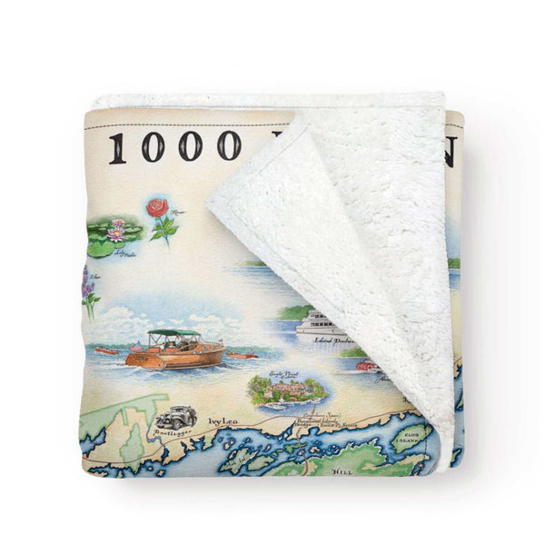 1000 Islands Map Fleece Blanket made of microfiber fleece and Berber fleece. The earth tone map features Eagle Point Castle, Bolt Castle, and Singer Castle. Flora includes Lilacs, Lily pads, and a rose. Activities like boating are also illustrated on the throw. 