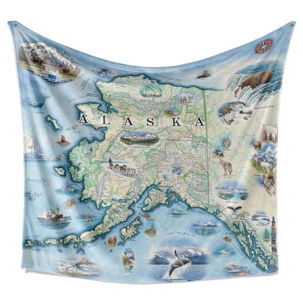 Hanging Alaska fleece blanket. The map includes Denali National Park and cities such as Anchorage, Fairbanks, and Juneau. Illustrations of wildlife matching the region: Polar bears, arctic foxes, moose, caribou, Gray wolves, Dall Sheep, wolverines, Canadian Lynx, King Salmon, Halibut, King Crab, horned puffins, harbor seals, Arctic Tern, ptarmigan, walruses, Kodiak bears, musk ox, Bald Eagles, Mountain Goats and more. 