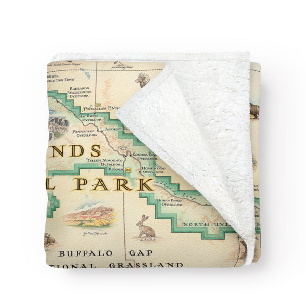 Badlands National Park Map fleece blanket in earth-tone colors. Featuring Vulture Peak, Red Shirt Table Overlook, Yellow Mounds, and Cedar Pass. A wide array of plants and animals such as: bison, elk, bighorn sheep, burrowing owls, plains leopard frogs, snapping turtles, pronghorn antelope, bobcats, mountain bluebirds, meadowlarks, coyotes, swift foxes, badgers, black-footed ferrets, prairie rattlesnakes, bald eagles, golden eagles, and turkey vultures. 