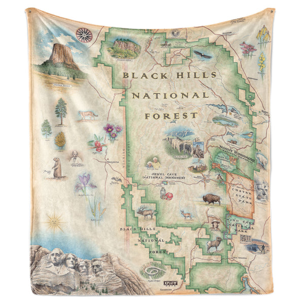 Hanging fleece blanket featuring a Black Hills National Forest map. The map features Mount Rushmore, Jewel Cave National Monument, Custer State Park, and Devil's Tower. The map also includes flora and fauna of areas such as Bison, Elk, Big Horn Sheep, Bald Eagle, Rocky Mountain Iris, and Buffalo Berries. 