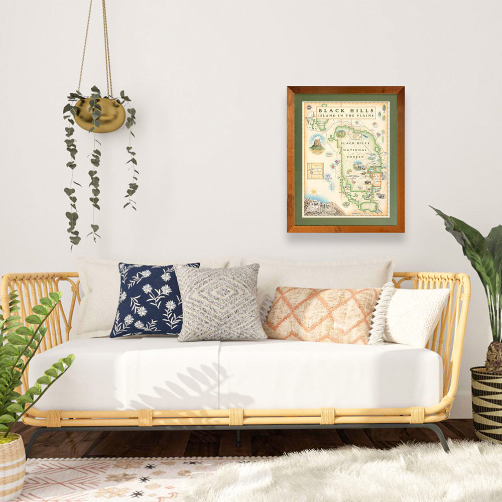 Black Hills National Forest hand-drawn map in a Montana Flathead Lake reclaimed larch wood frame and green mat hanging over a day bed with plants on both sides. 