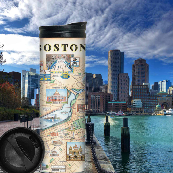 Boston City Map Travel Drinkware sitting next to the  Charles River.  In the background, you can see the city. The map features Featuring Boston Strong, Boston Marathon, Fenway Park, Museum of Fine Arts, Massachusetts State House, and Bunker Hill Monument.