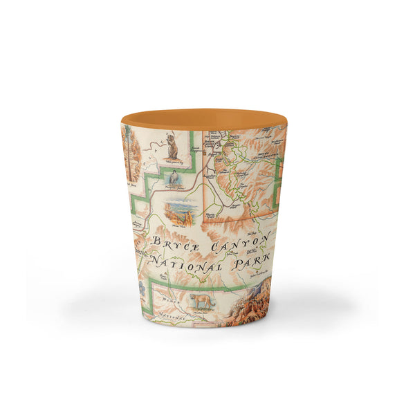 Bryce Canyon National Park Map ceramic shot glass on earth tone colors featuring canyons, horseback, hoodoos, Rim Trail, Sunrise Point, Sunset Point, Inspiration Point, and Bryce Point.