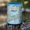 Cape Cod Map ceramic coffee mug sitting on a tree stump. Featuring Plymouth Rock, fish, crane, fox, Provincetown, canoeing, biking, beach, lighthouse, and ocean. Blue- 16oz