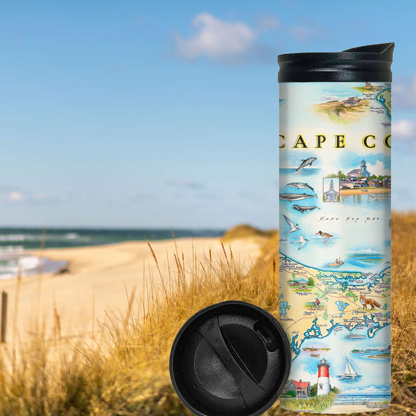 Cape Cod Travel Mug sitting in the hook-shaped peninsula of the U.S. state of Massachusetts on the beach with grass. 